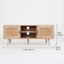 Mueble de TV de color madera clara con puertas de ratán y estantes centrales abiertos en estilo nórdico.
