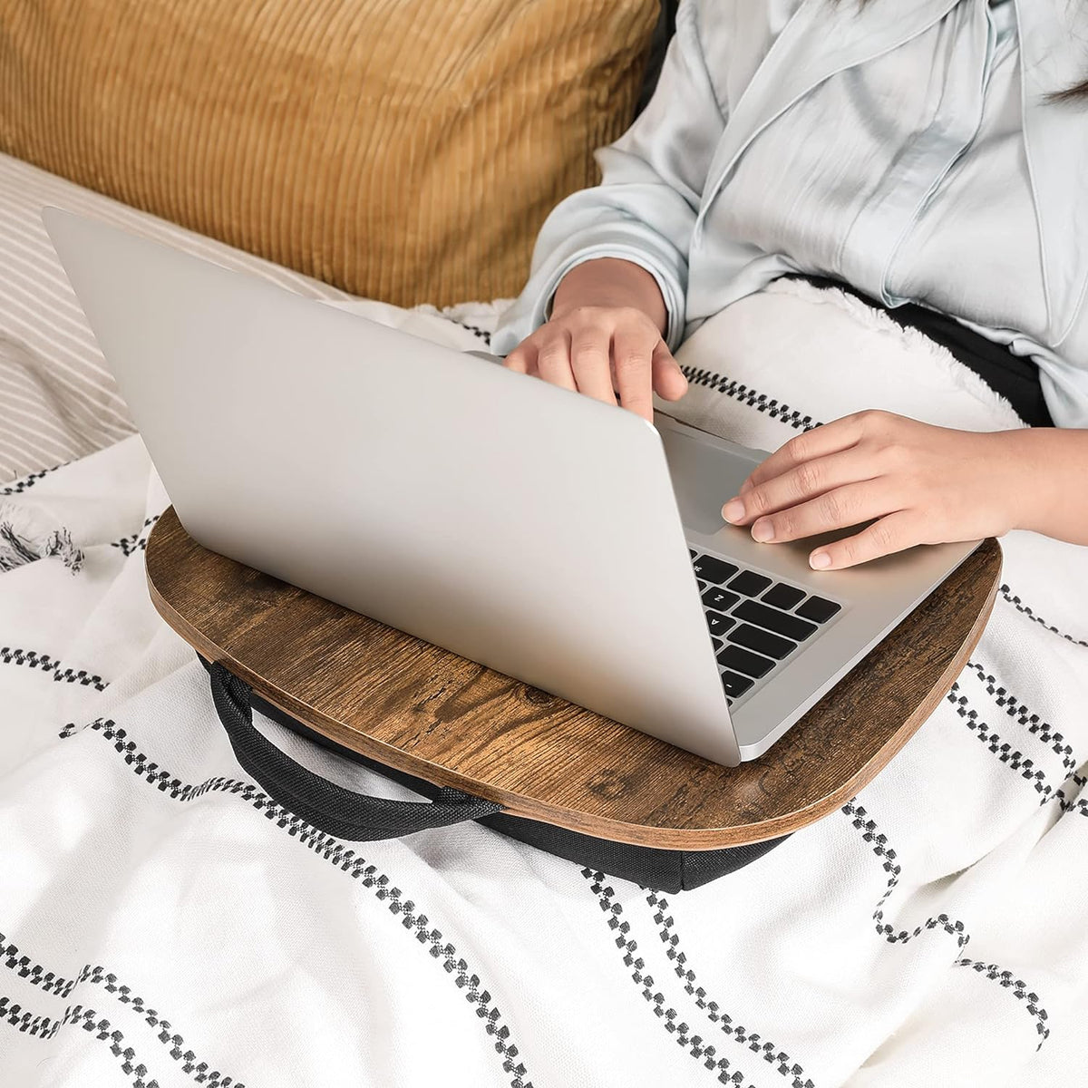 Mesa para notebook con cojín Sylan sobre las piernas en la cama