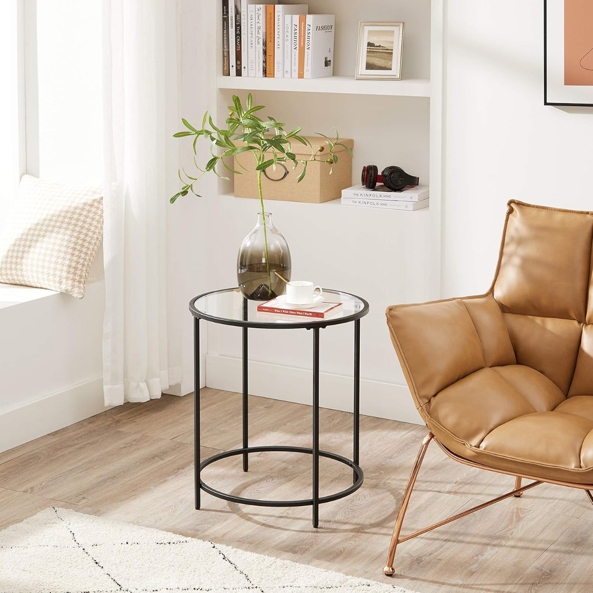 Mesa auxiliar de vidrio Idre junto a un sillón con una planta